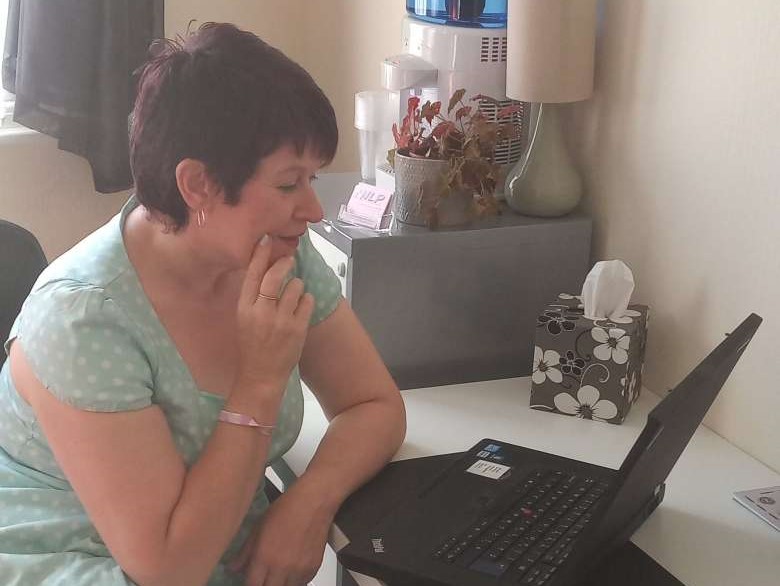 Emma Cox sitting at a desk looking at a laptop where she's having a Zoom call with a client
