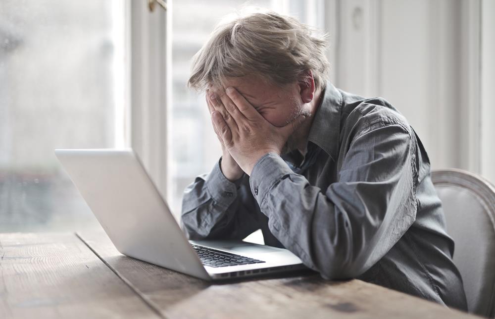 Male addict in despair sitting at his laptop